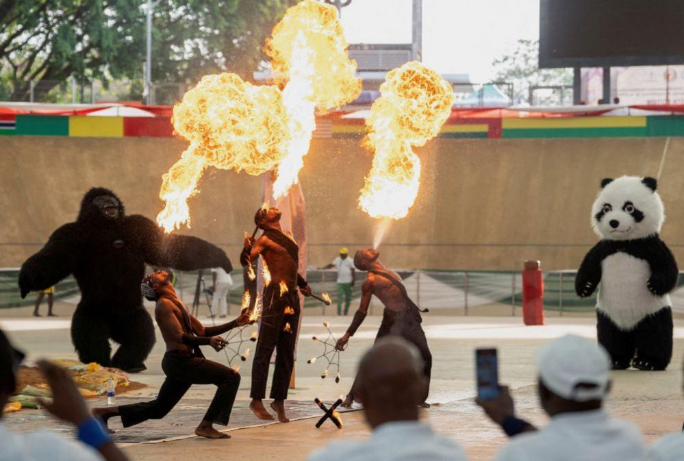 Three fire breathers perform at the closing ceremony of the ECOWAS Africa Wrestling Tournament. They are surrounded by a giant panda and gorilla costume - Saturday 8 March 2025.