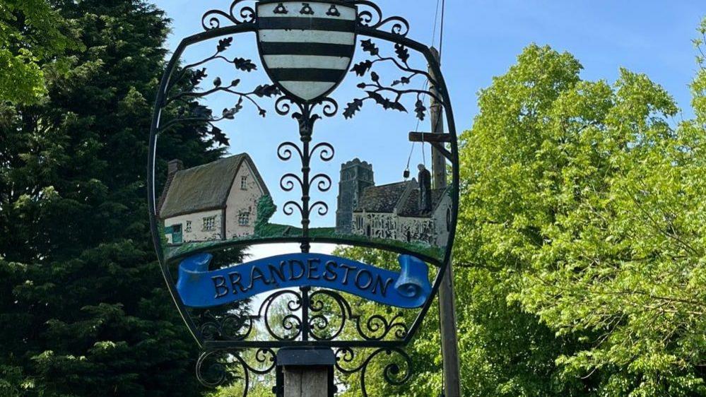 Village sign for Brandeston showing house and church