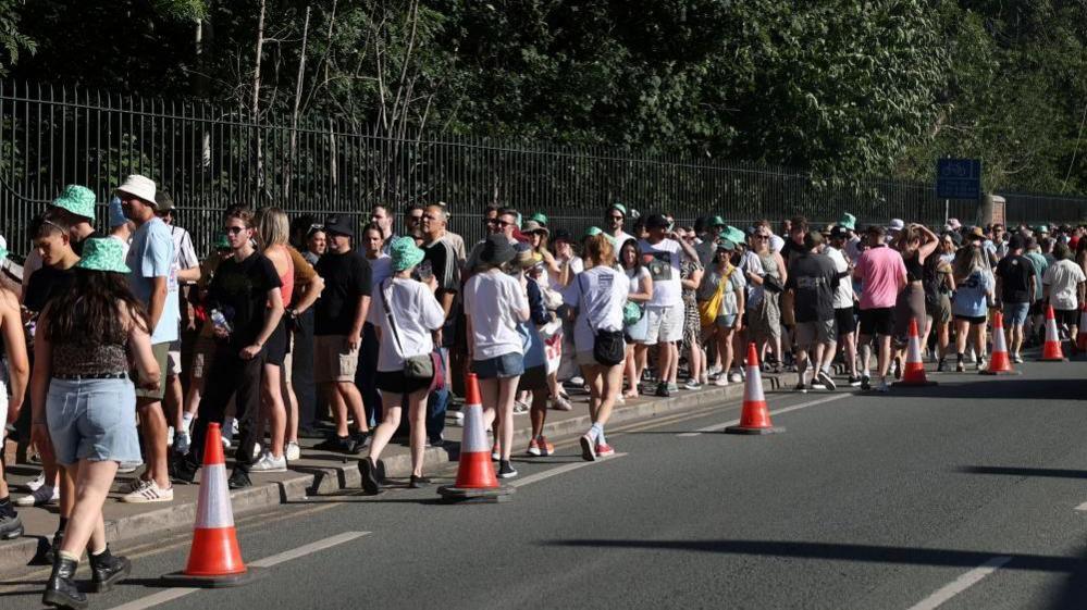 A long line of Oasis fans, with many wearing bucket hats, can be seen queuing outside Heaton Park