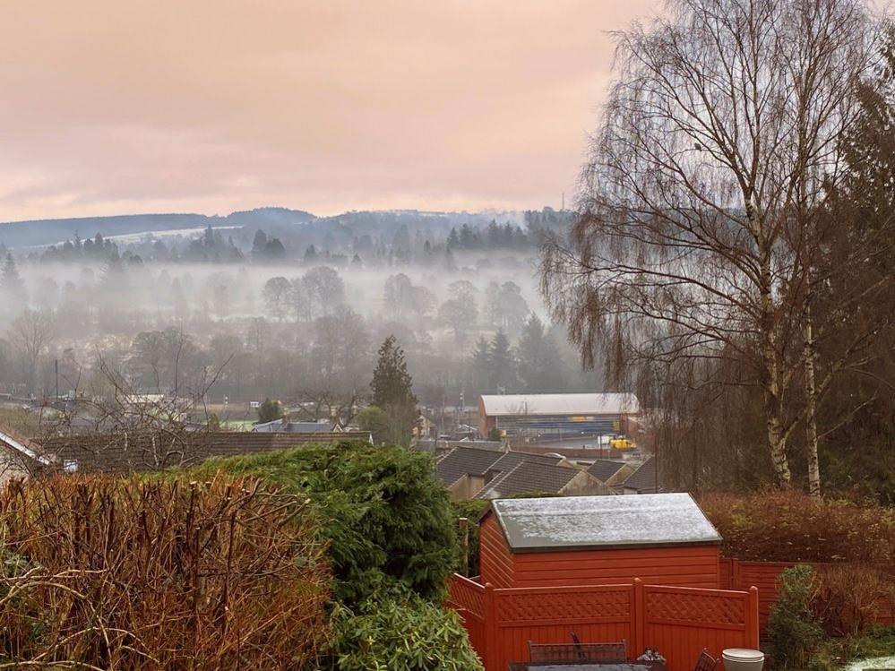 A light fog hangs over the rooftops and forest near Dunblane.