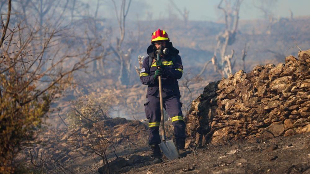 A firefighter takes part in extinguishing the fire that broke out in an olive grove in the Moria region, on Lesvos island, northeast Aegean