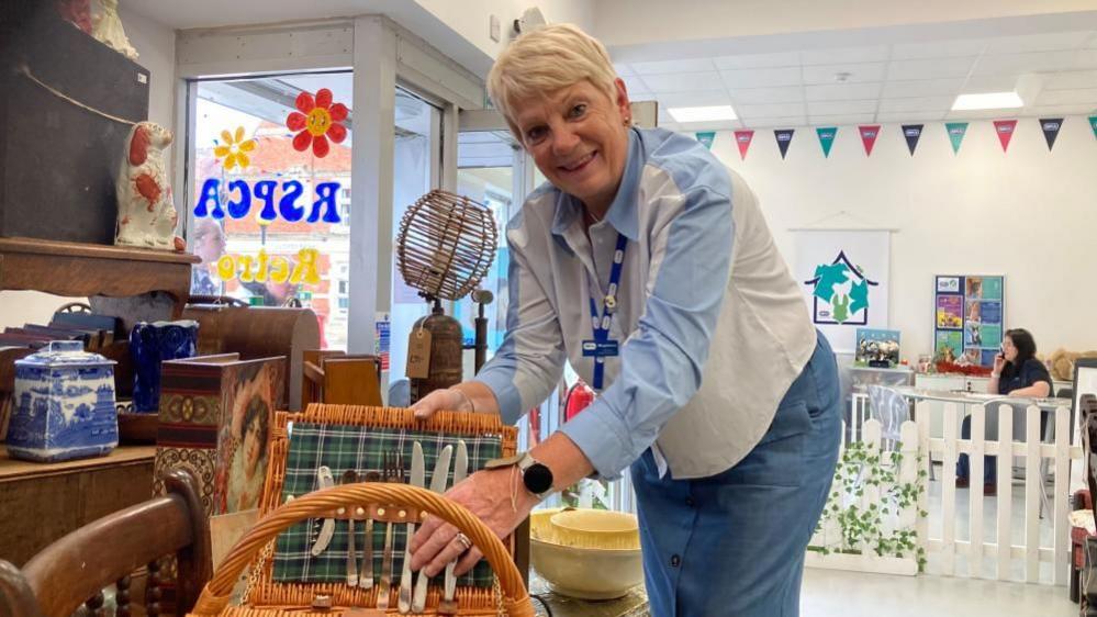 Magdalena Dawson with short light-coloured hair adjusts a picnic hamper