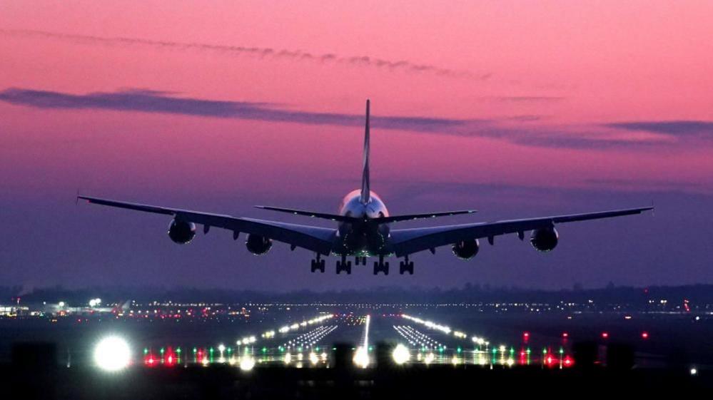 An Emirates Airbus A380 lands during sunrise at London Gatwick Airport.