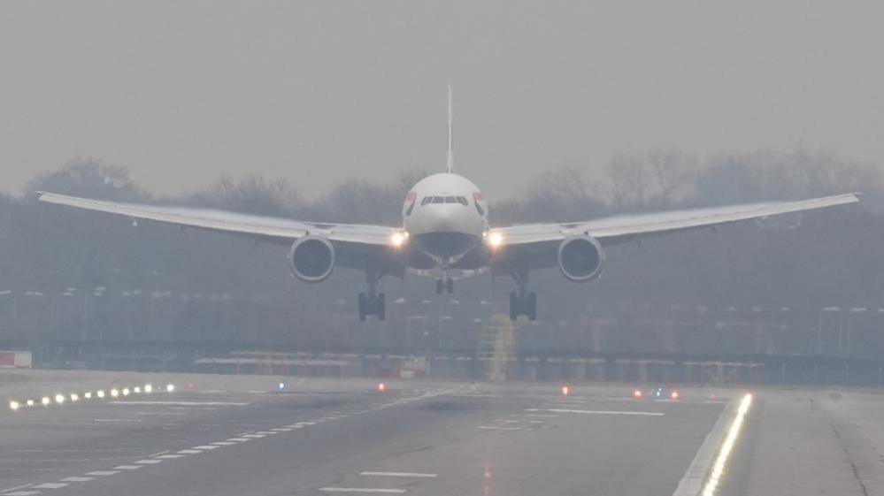 A front-on angle of a British Airways just above the runway at Gatwick Airport as it lands during foggy conditions