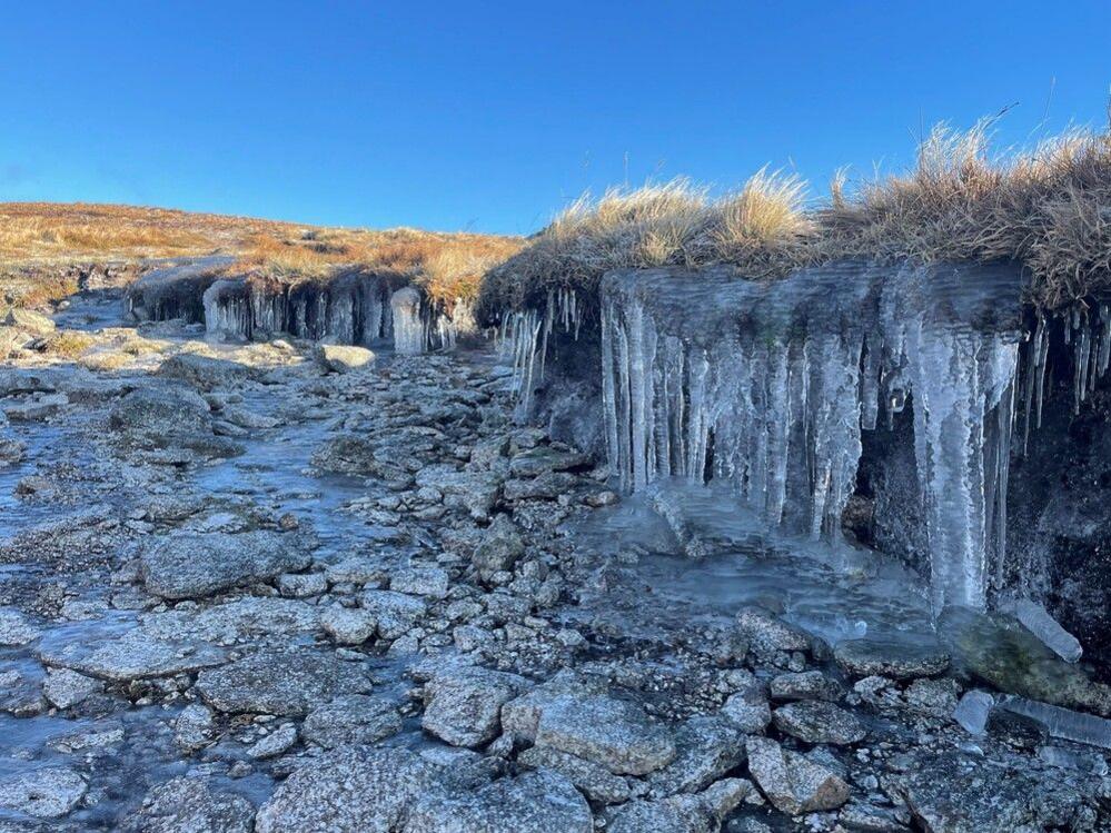 Icicles hang down into a frozen burn with rocks in Cairnsmore of Fleet, Galloway