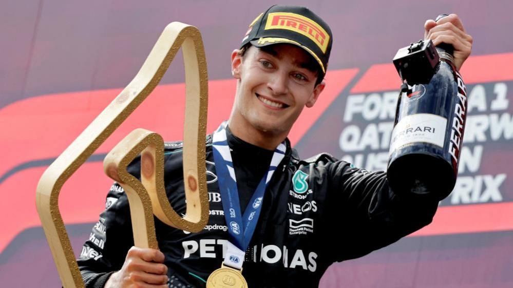 George Russell wearing Pirelli cap and holding a trophy