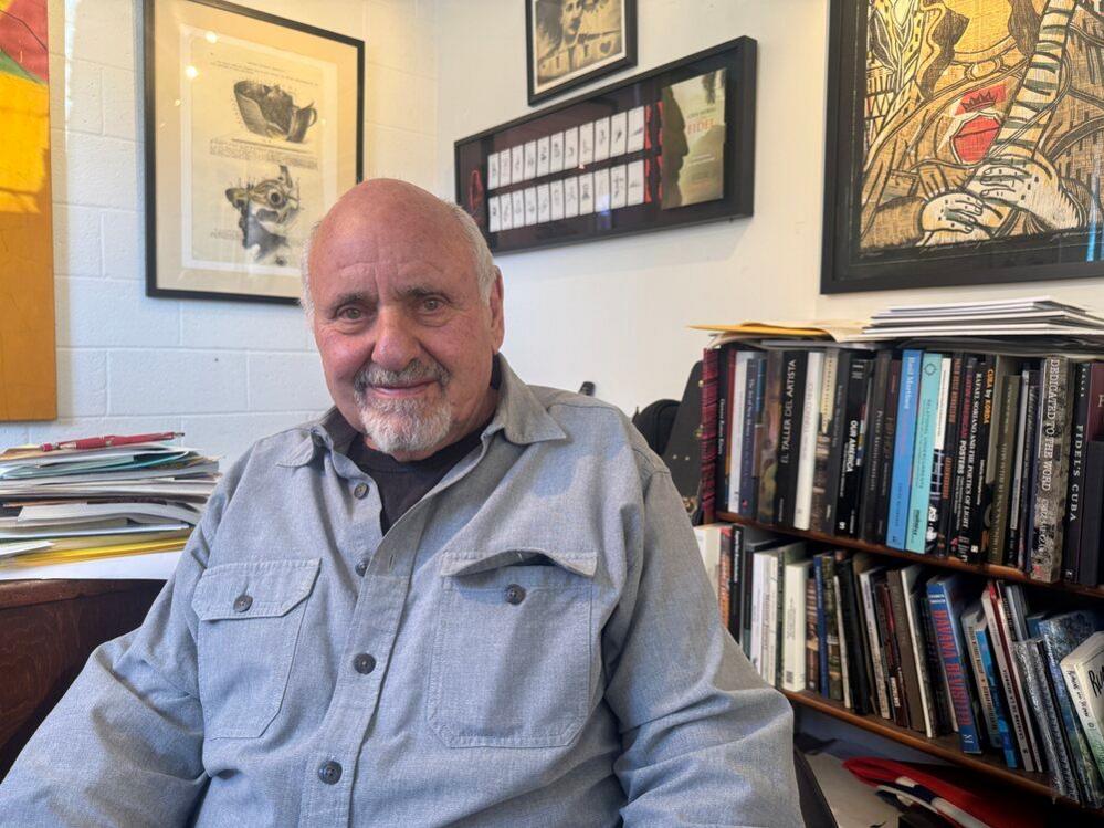 A man wearing a grey shirt sits in front of a book case