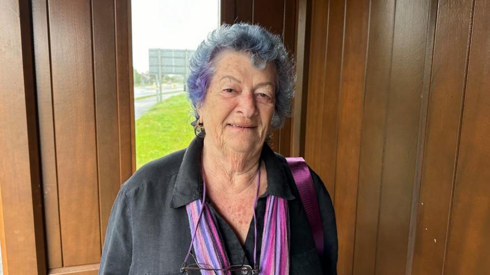 Sandy Maitland wearing pink scarf and glasses on string