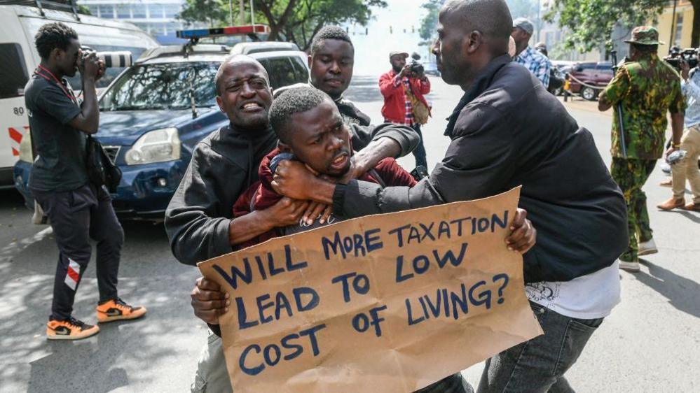 Kenyan plain clothed police officers detain an activist during a protest over tax hike plans in Nairobi on June 6, 2023