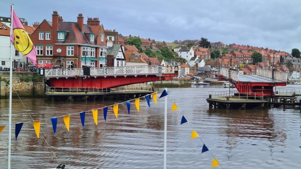 Whitby's swing bridge with the town in the background and blue and white bunting in the foreground.