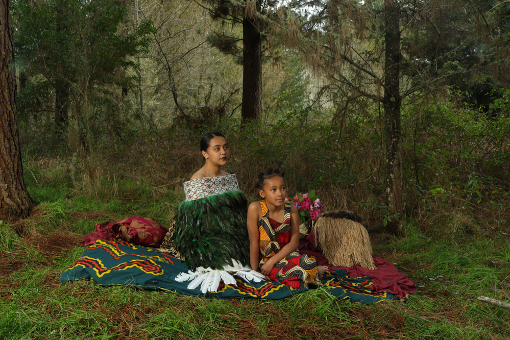 Two girls dressed in traditional Igbo and Māori garments and accessories.