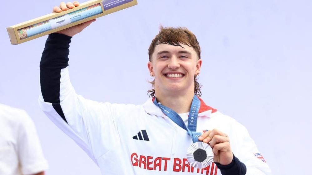 Kieran Reilly smiling in Team GB top with silver medal