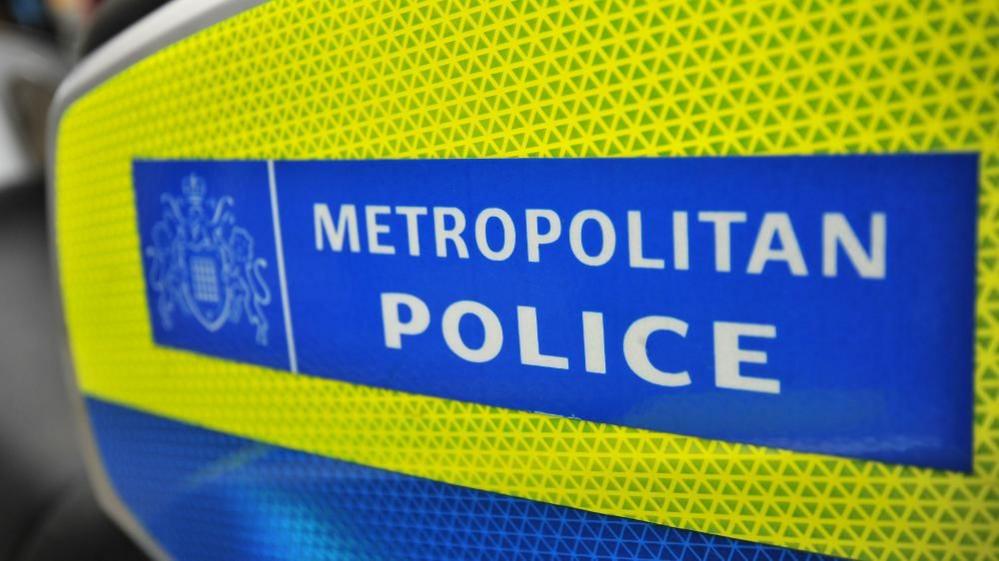 A yellow and blue sign with the words METROPOLITAN POLICE written in white capital letters