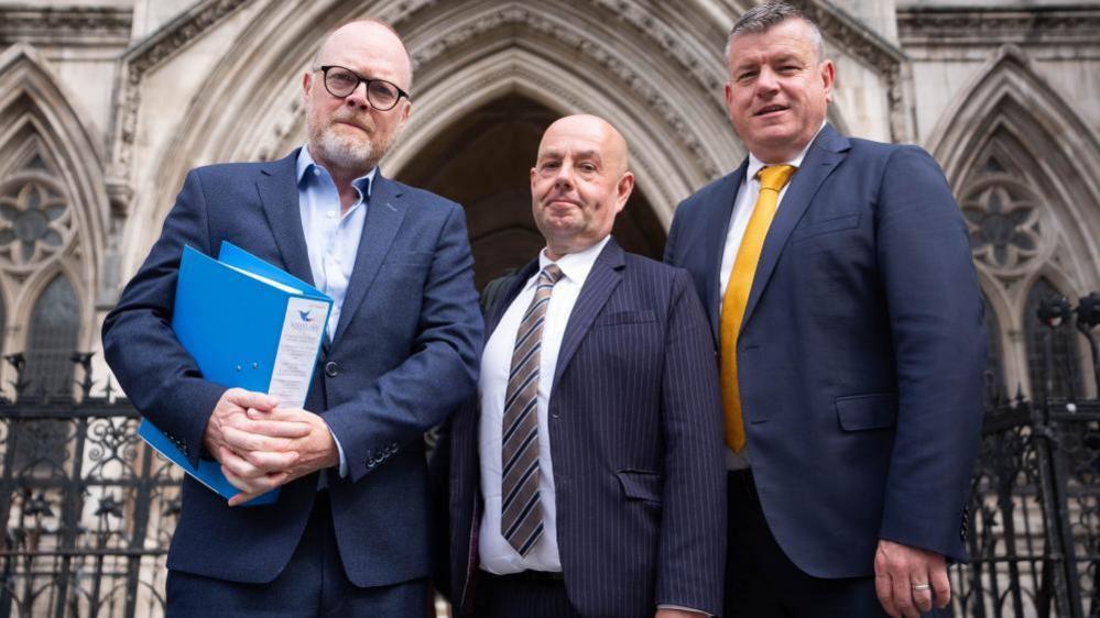 Three men in suits outside court