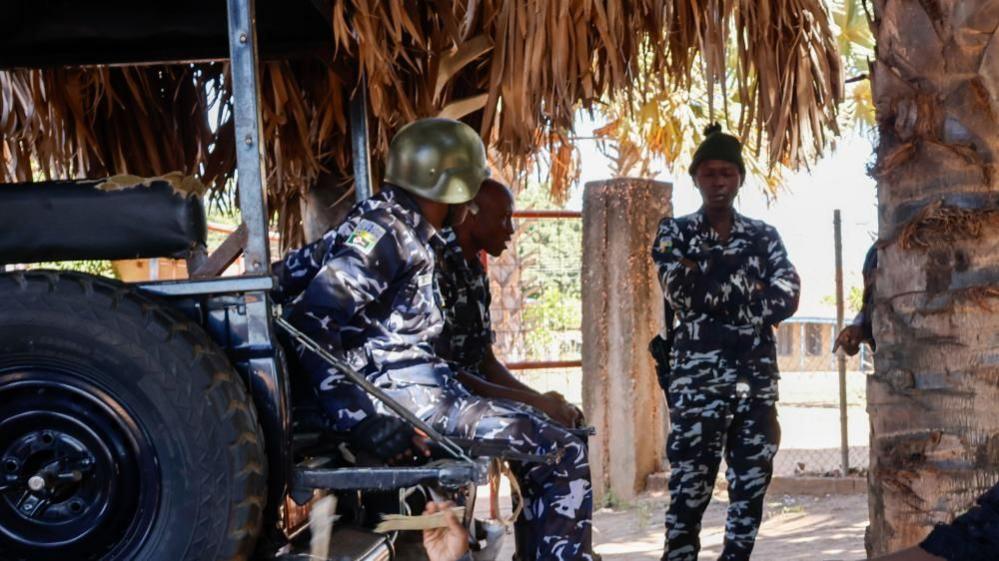 Three police officers are seen outside the school from where children were abducted in Papiri village in Nigeria's Niger state