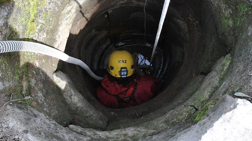 person going down well in protective gear