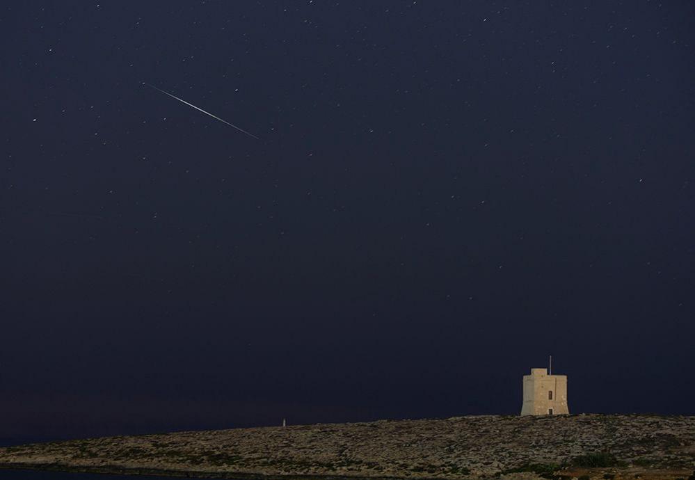 A meteor streaks through the night sky behind St Mark's Tower in Malta