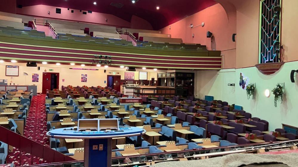 The view of the disused bingo seats and tables in the stalls with the circle above visible - as seen from the stage.