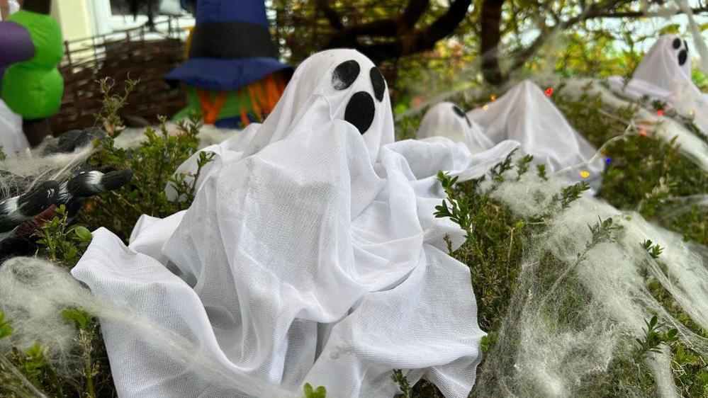 A close-up of a ghost made out of fabric on a hedge