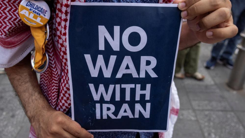A demonstrator holds an anti-war sign during a protest against Israeli strikes on Iran