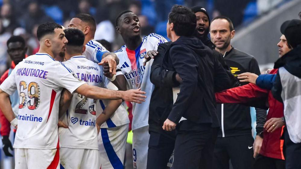 Paulo Fonseca has to be pulled away from the referee by his Lyon players