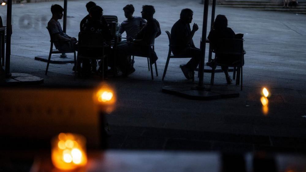 People use candles at a pub in Ourense, Galicia, northwestern Spain, amid a power outage, 28 April