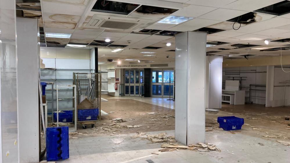 The empty former Debenhams store in Bedford, where parts of a ceiling have fallen down, empty boxes are strewn about and electrical cables can be seen 