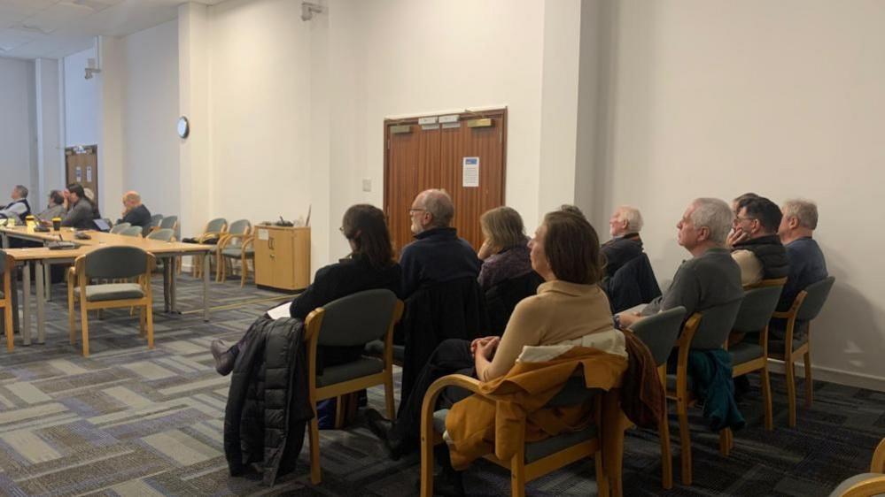 A crowd of residents listen intently as a discussion gets underway at a council meeting.