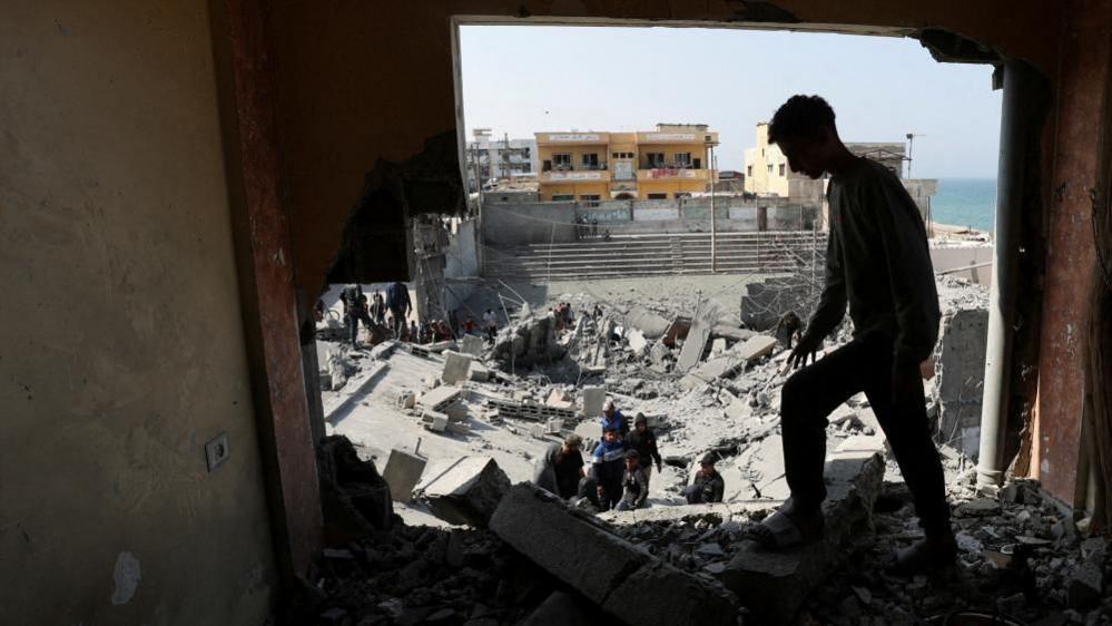 Palestinians inspect the site of an Israeli strike on a residential building, in Deir al-Balah in central Gaza.