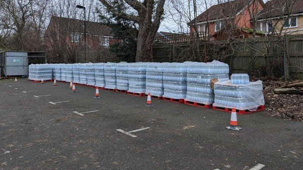 Bulk shipments of bottled waters in a car park.