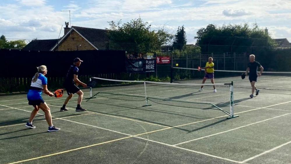 Four people playing pickleball