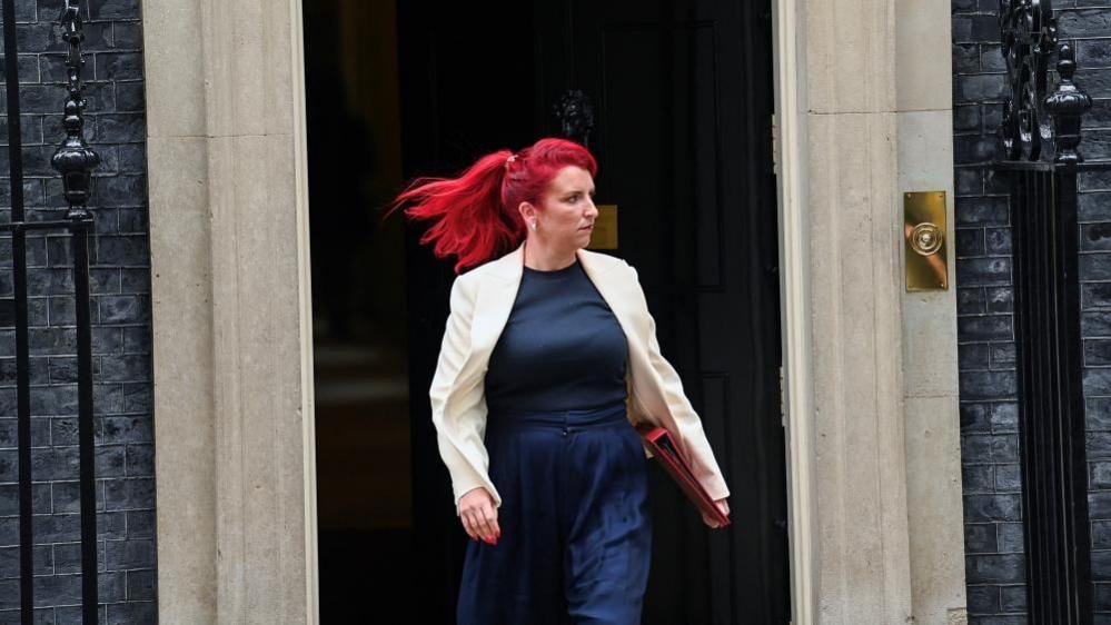 Woman with red hair walking and holding red file