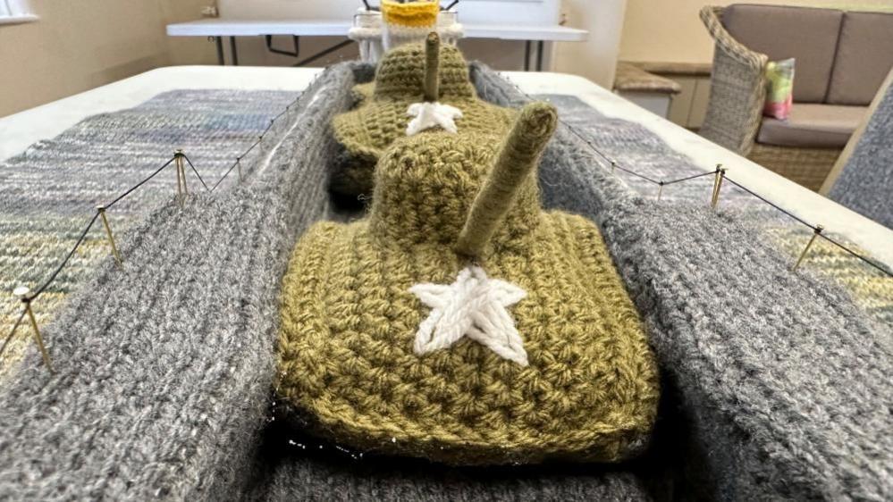 Two knitted tanks with stars on the front crossing the bridge