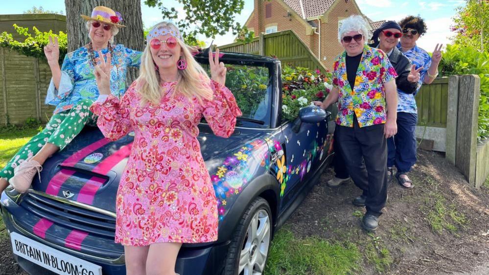 Members of Filby in Bloom's committee pose next to a car filled with flowers