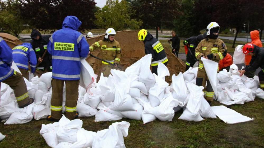 Firefighters build barriers with sandbags against flood water, near the river Biala Glucholaska, in Glucholazy, southwestern Poland, 14 September 2024. 