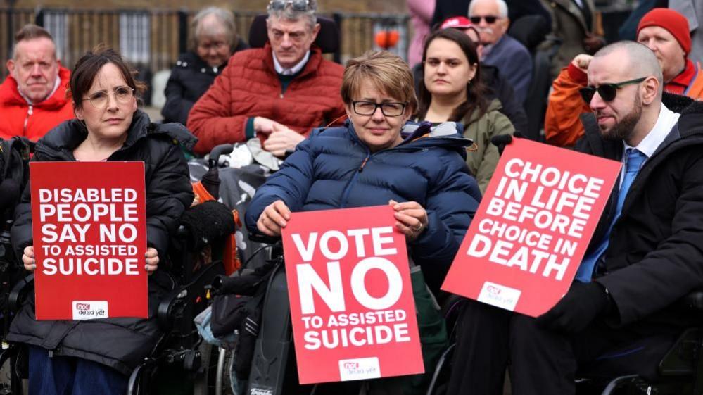 Former Paralympian Baroness Tanni Grey-Thompson (C) holds a banner which reads "Vote No to Assisted Suicide" alongside other disabled activists against the Assisted Dying Bill outside Parliament in London on 24 March 2025.