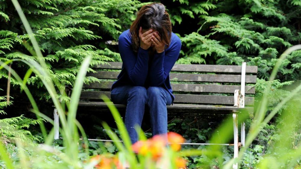 A woman sitting on a bench with her head in her hands