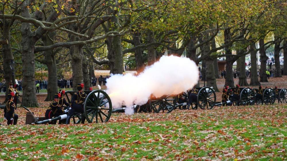 Soldiers of the King's Troop Royal Horse Artillery in ceremonial uniform fire a 41-gun salute from horse-draw guns at Green Park in central London. Smoke can be seen coming from the muzzle of one of the six guns seen in this photograph