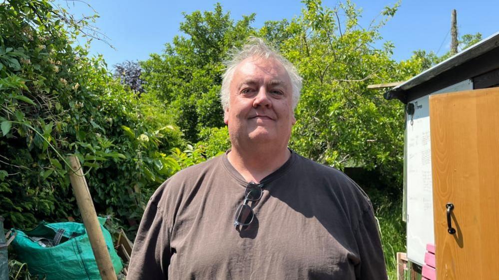 Scott McMillan in front of a shed