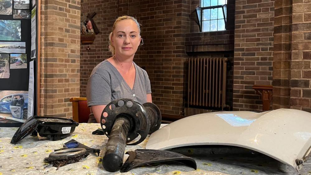 Ms Keating sat behind a table which showcases damaged car parts collected from the Carlton Hill area.