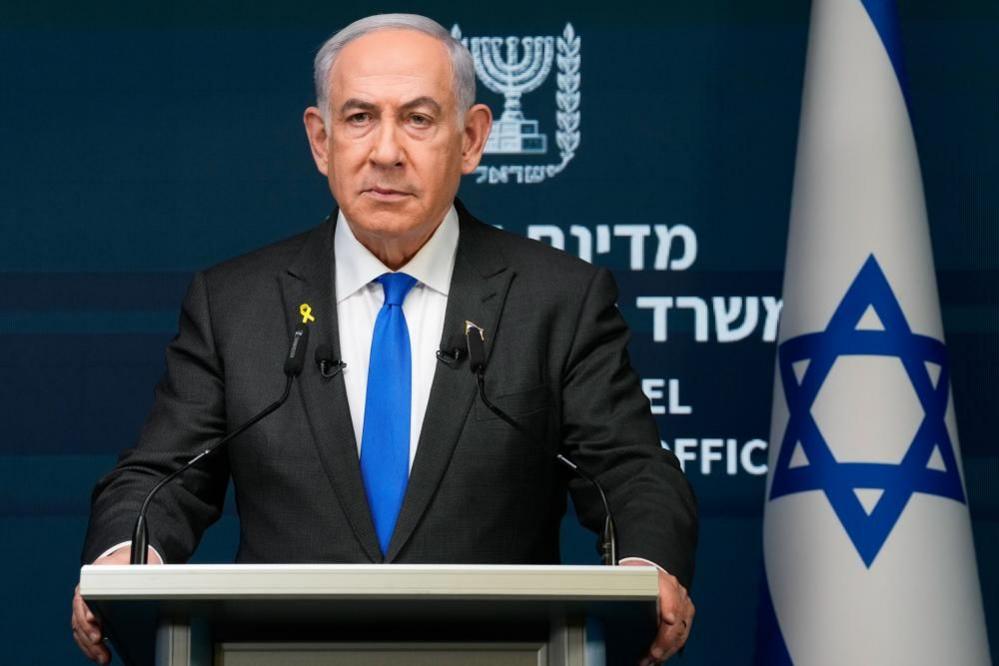 Benjamin Netanyahu stands at a lectern with an Israeli flag to his left