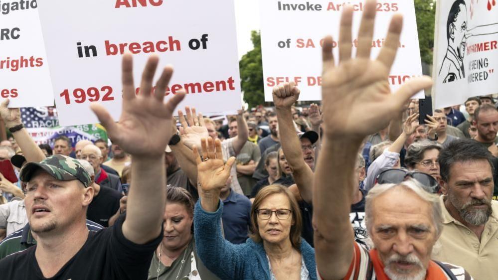 With hands raised, Afrikaners picket in support of an executive order by US President Donald Trump, granting Afrikaners refugee status outside the US Embassy in Pretoria, South Africa, 15 February 2025