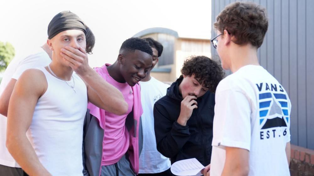 Mazvita Hlubanyana (centre pink shirt) reacts as he receives A-level results with friends at The Latimer Arts College in Barton Seagrave, Northamptonshire. 