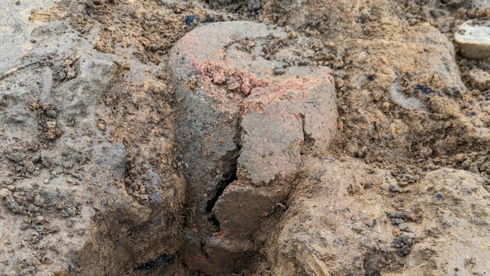 A broken clay pot in wedged upside in the dirt