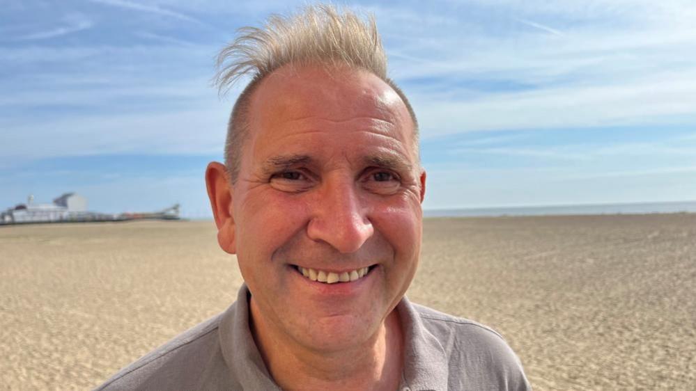 Trevor Rawson standing on the beach with the Britannia Pier in the background