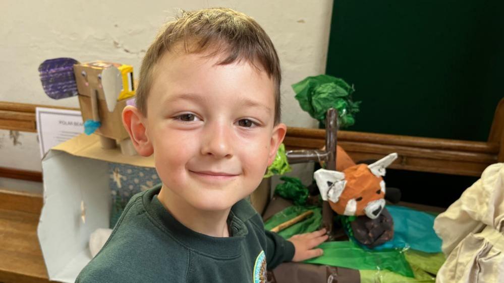 Elliott standing near his model of a red panda