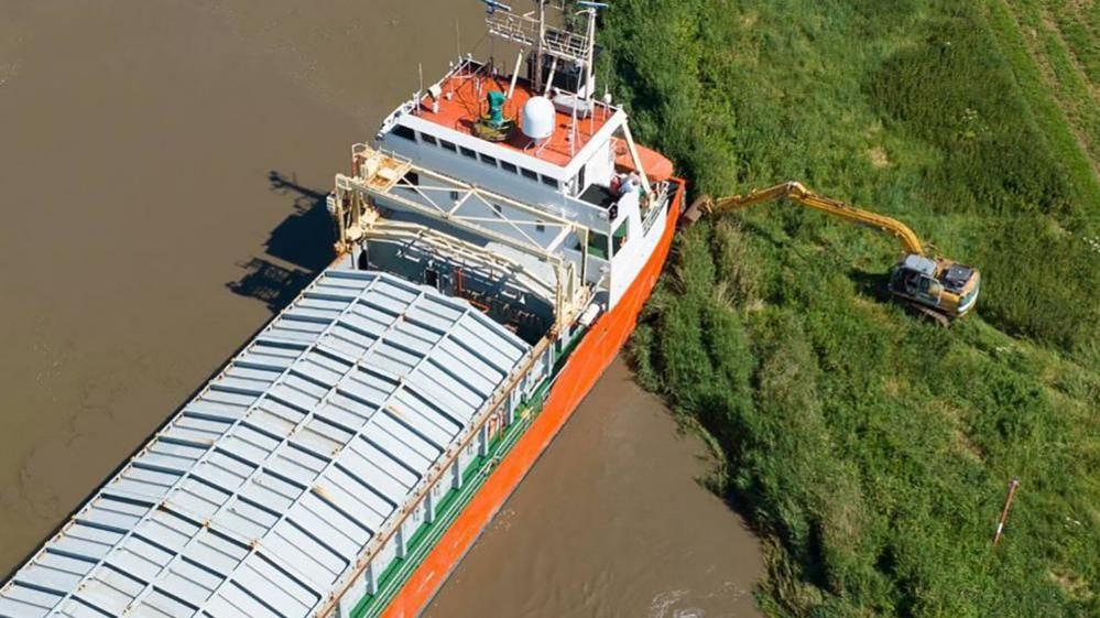 Digger working alongside ship