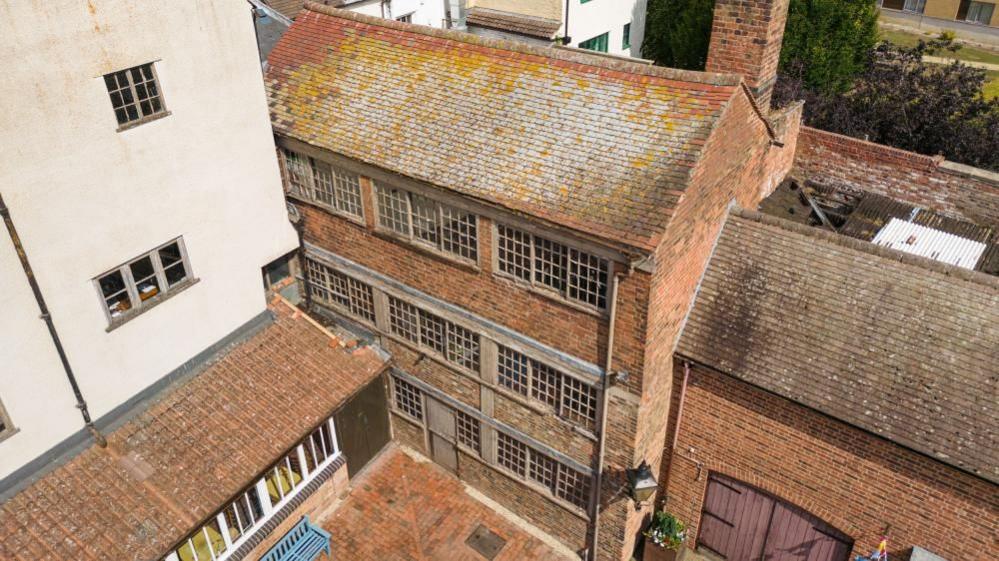 Aerial view of the Pin Factory at the Folk of Gloucester complex. Shows building's exterior with original windows and restored courtyard. 