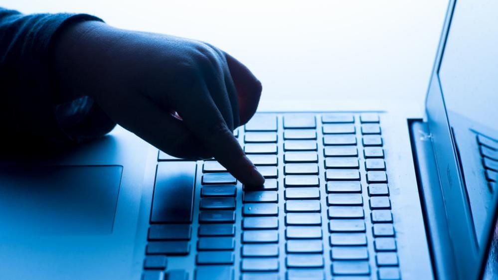 A child's finger on the keypad of a laptop computer