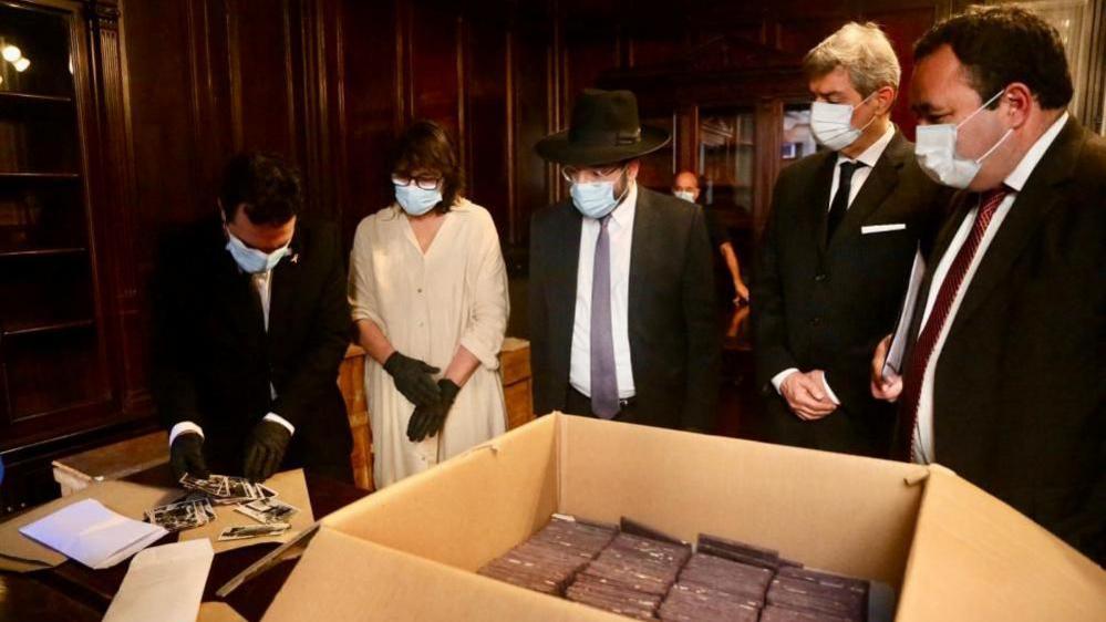 Officials from Buenos Aires' Holocaust Museum and from Argentina's Supreme Court examine photographs confiscated by local authorities when it was shipped to Argentina in 1941.